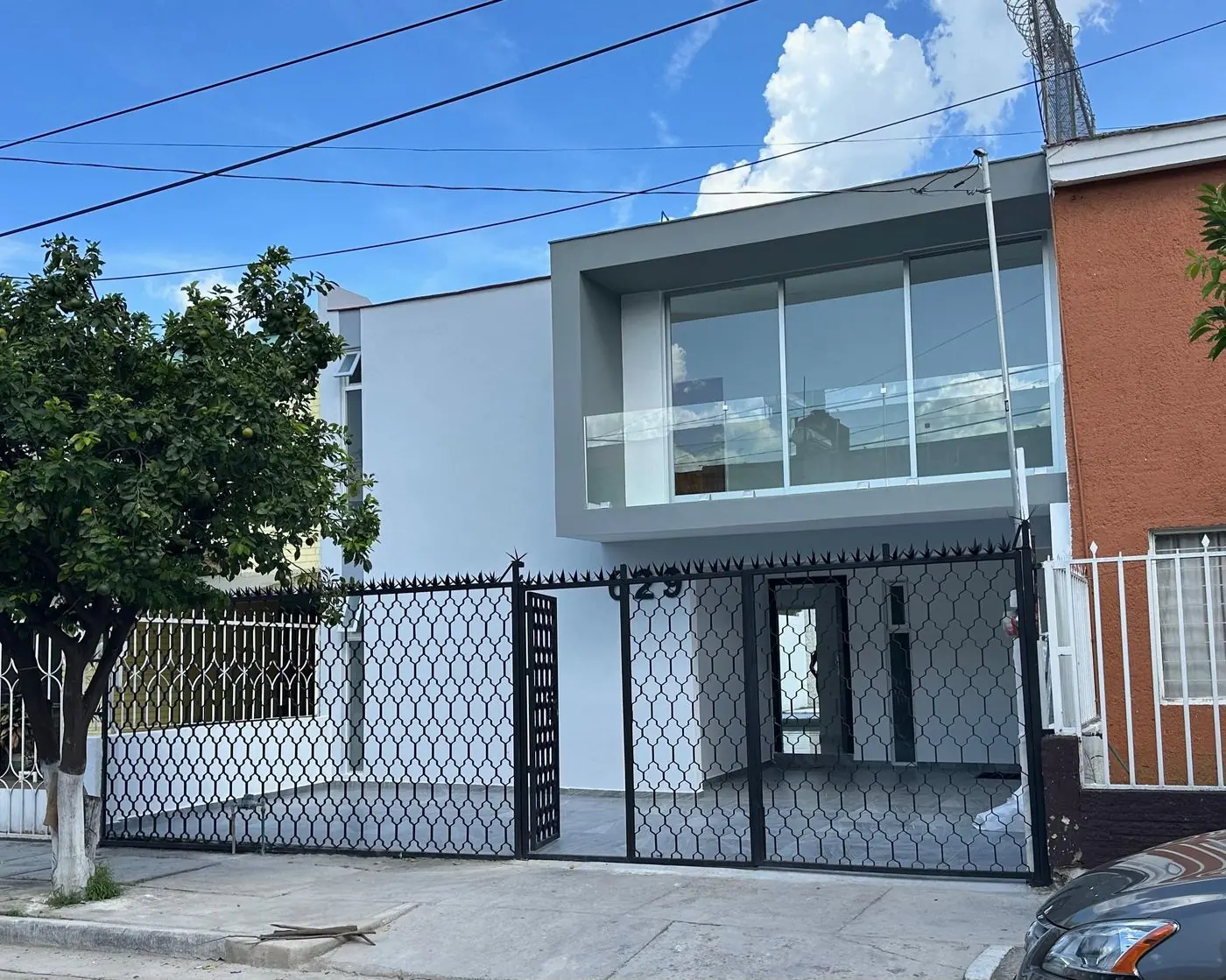 Fachada terminada de Sutaj con balcón de cristal y reja negra